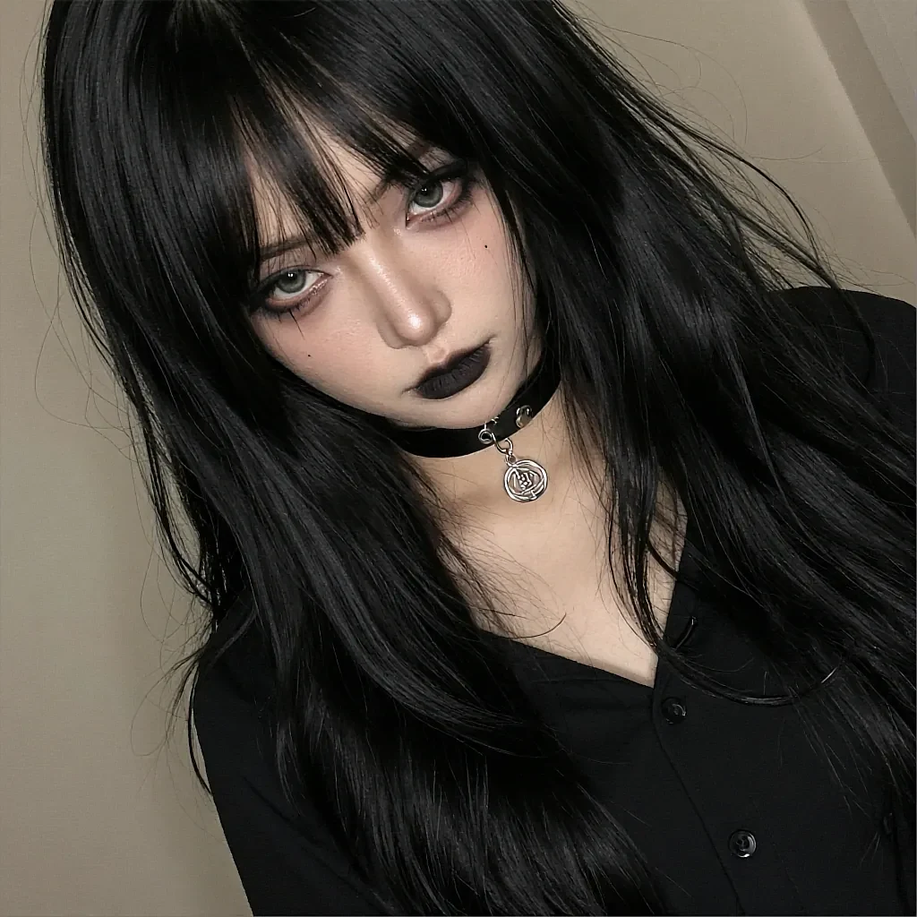 Black-haired woman with bangs and green eyes wearing black lipstick and a silver pendant choker